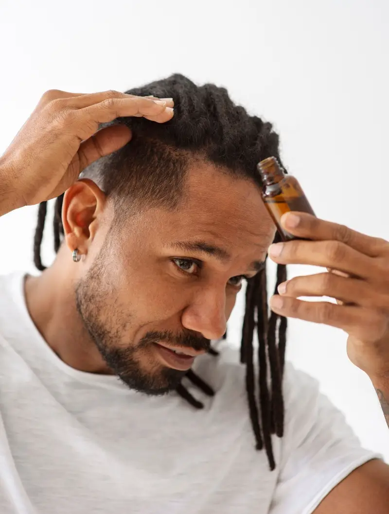 Close up smiley man applying hair treatment